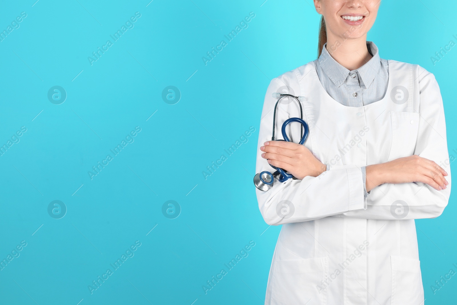 Photo of Female doctor holding stethoscope on color background, closeup with space for text