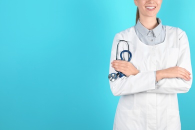 Female doctor holding stethoscope on color background, closeup with space for text