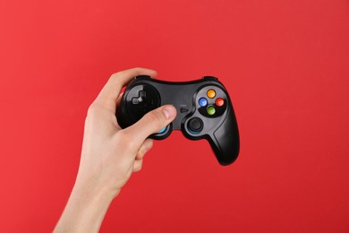 Photo of Man using wireless game controller on red background, closeup