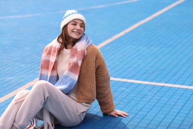 Beautiful woman in warm scarf and hat outdoors, space for text