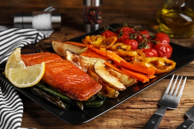 Tasty cooked salmon and vegetables served on wooden table, closeup. Healthy meals from air fryer