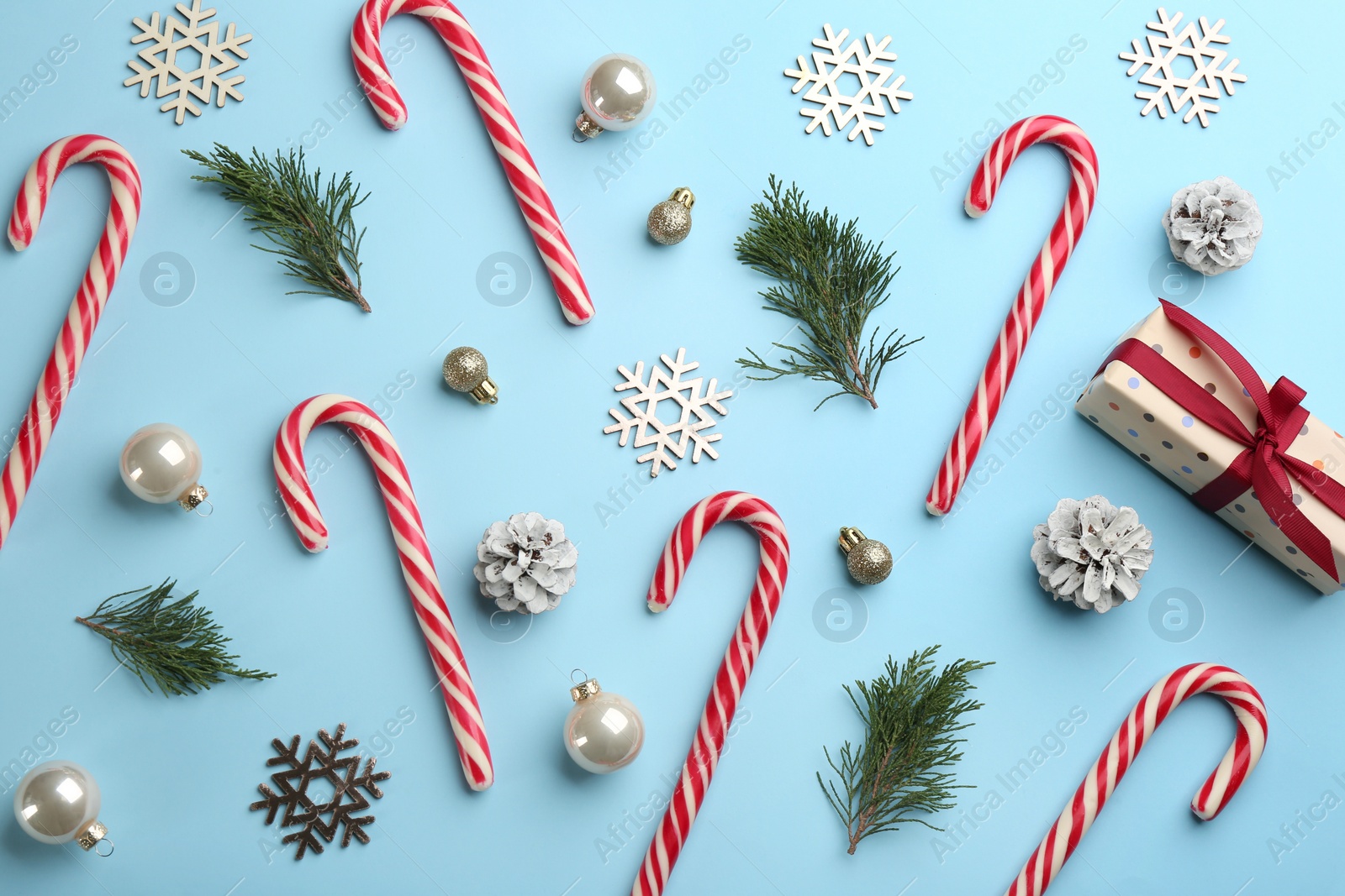 Photo of Flat lay composition with candy canes and Christmas decor on light blue background