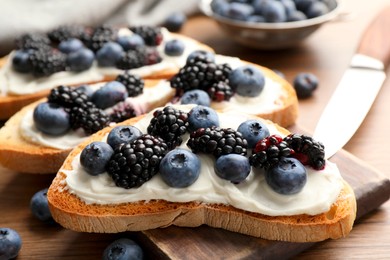 Photo of Tasty sandwiches with cream cheese and berries, closeup
