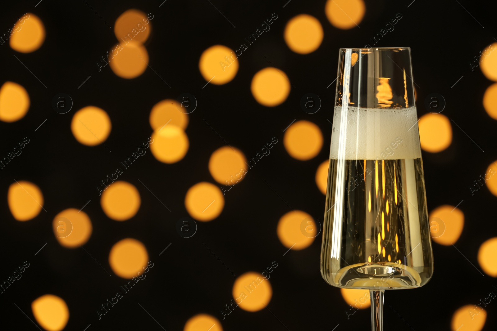 Photo of Glass of champagne against blurred lights. Space for text