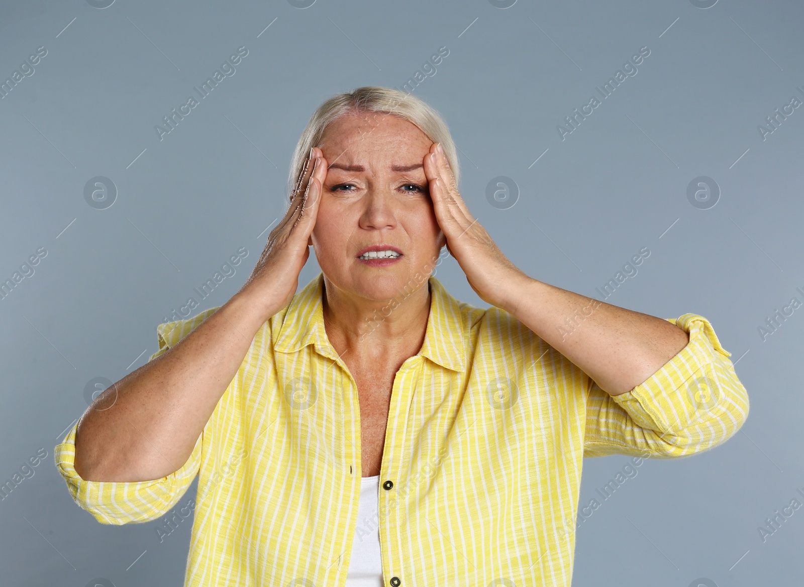 Image of Mature woman suffering from headache on grey background