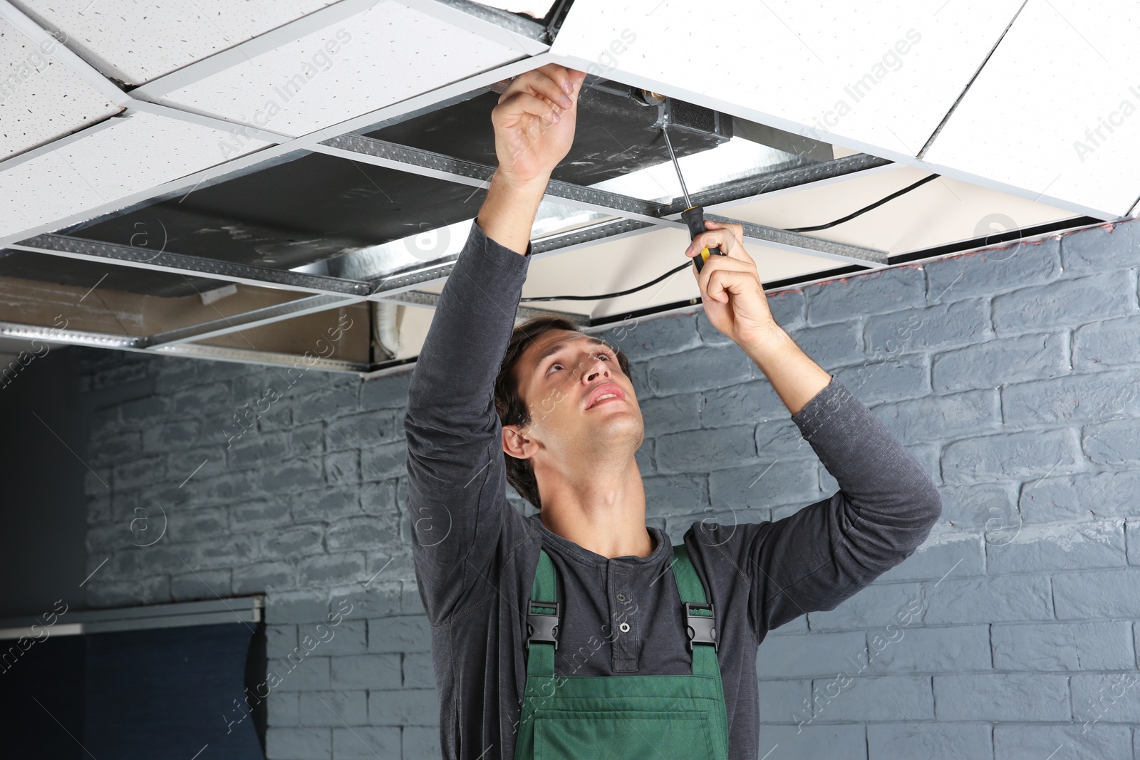 Photo of Young male technician repairing air conditioner indoors