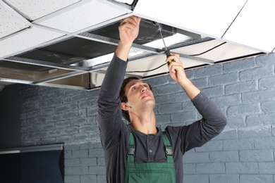 Young male technician repairing air conditioner indoors