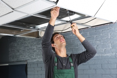 Photo of Young male technician repairing air conditioner indoors