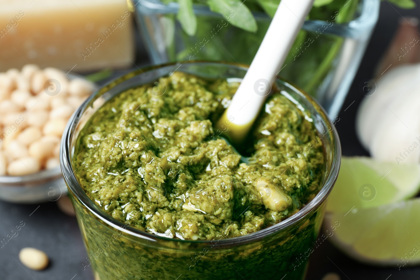 Photo of Glass of tasty arugula pesto on table, closeup