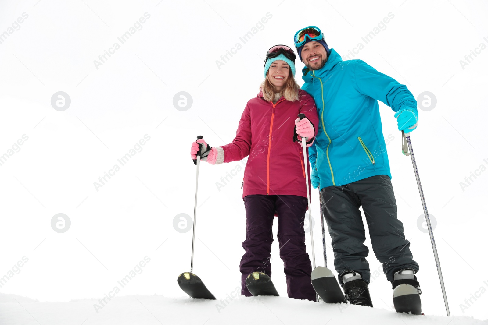 Photo of Couple of skiers on slope at resort, space for text. Winter vacation