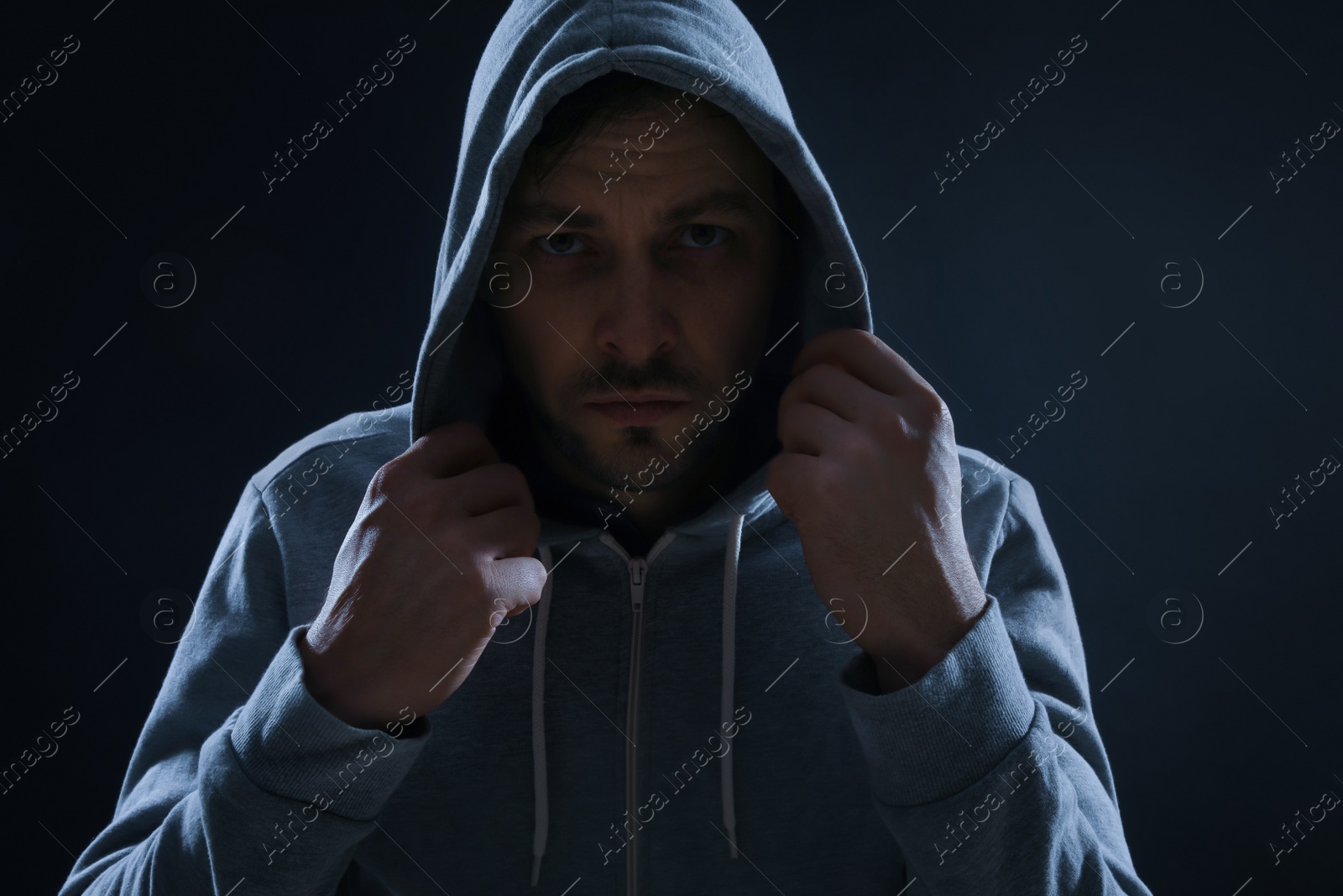 Photo of Mysterious man in hoodie on dark background. Dangerous criminal