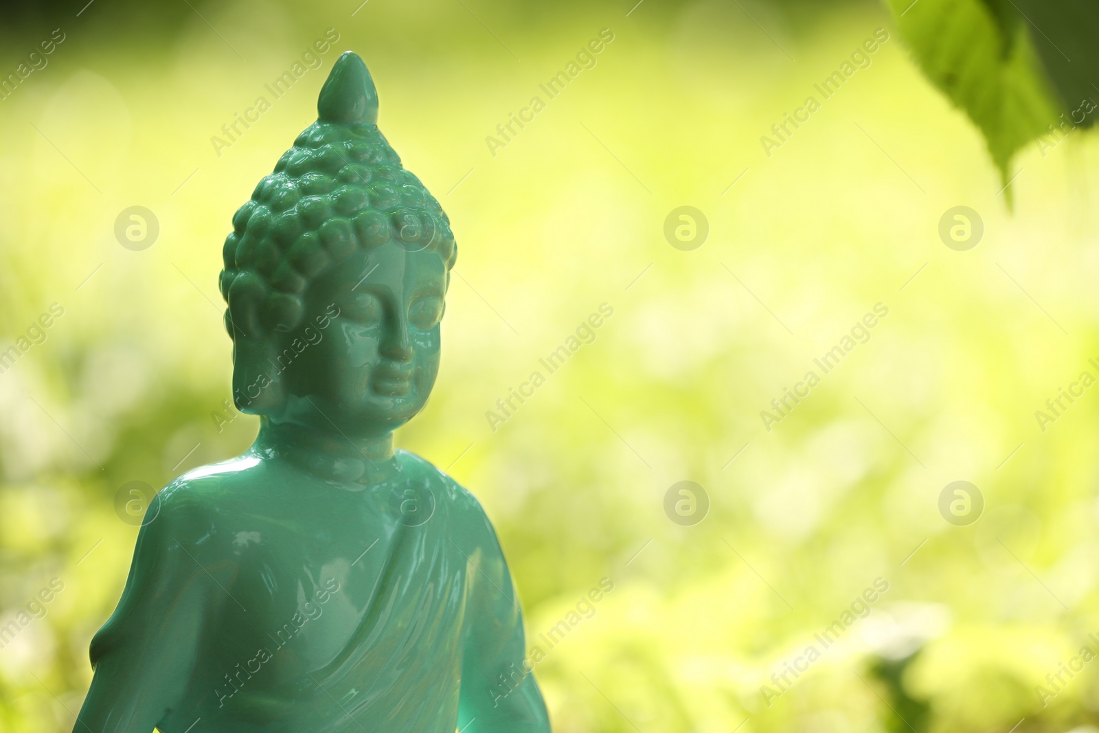 Photo of Decorative Buddha statue on blurred background outdoors. Space for text