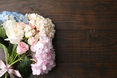 Bouquet of beautiful hydrangea and rose flowers on wooden background, top view. Space for text