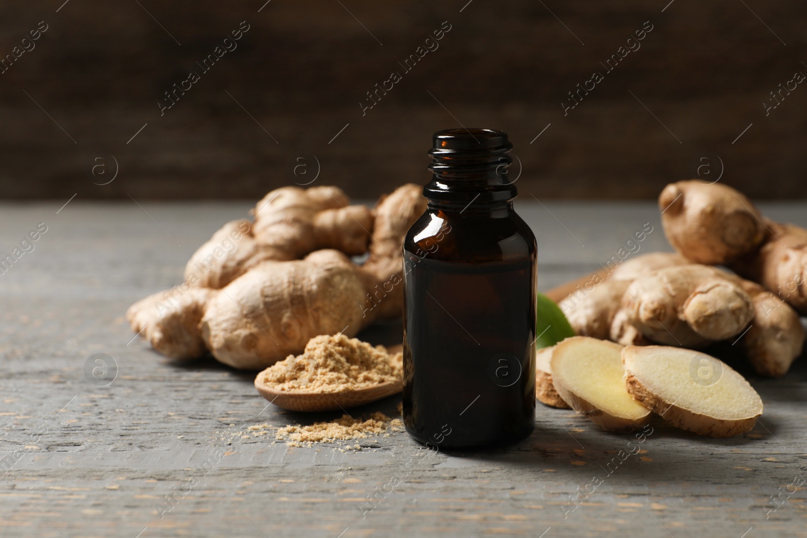 Photo of Ginger essential oil in bottle on light grey table