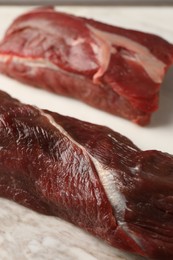 Photo of Pieces of raw beef meat on marble board, closeup