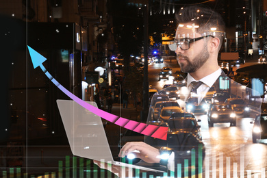 Image of Double exposure of businessman with laptop and night cityscape. Stock exchange trading