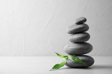 Photo of Stack of zen stones and bamboo leaves on table against light background. Space for text