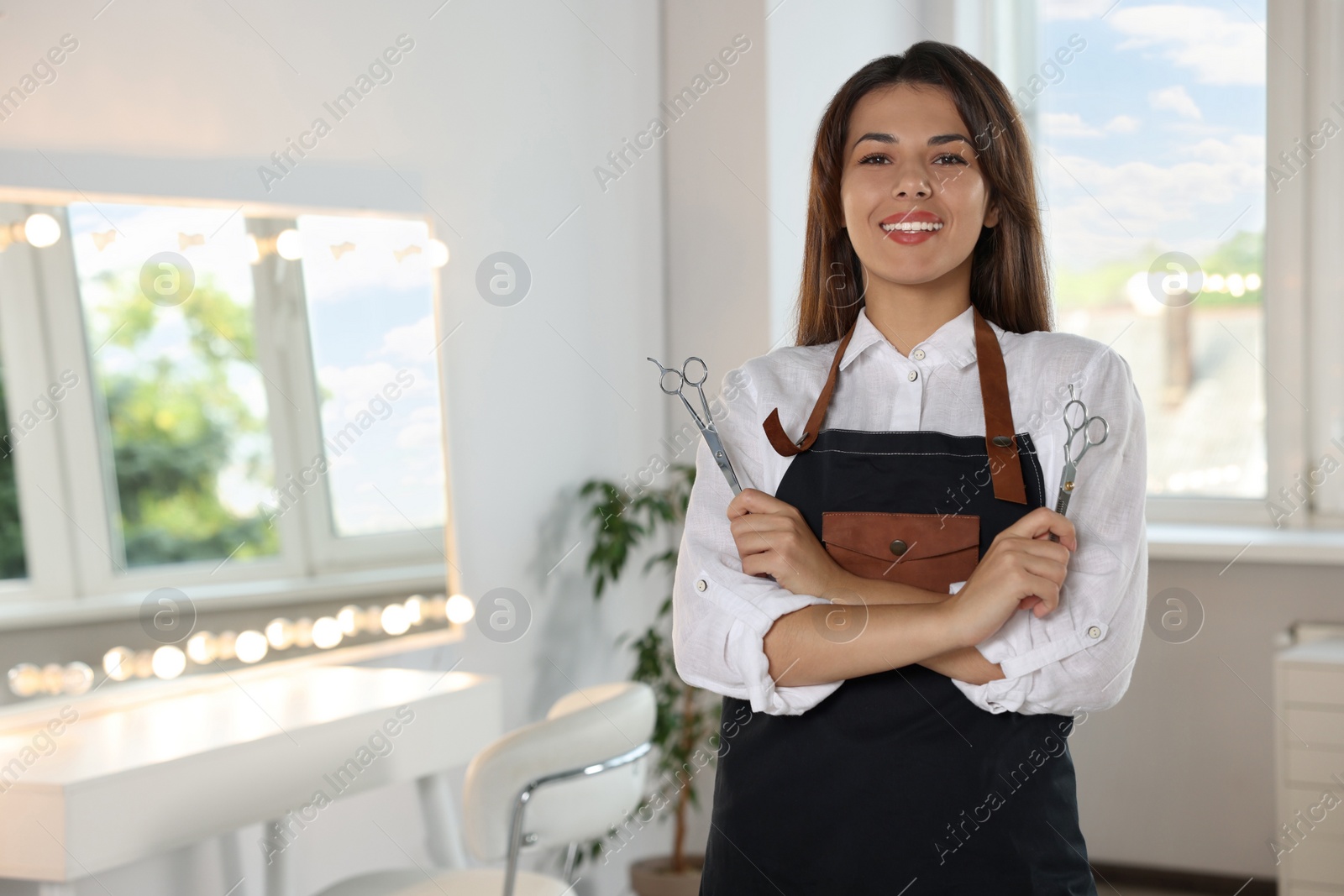 Photo of Portrait of happy hairdresser with professional scissors in beauty salon. Space for text