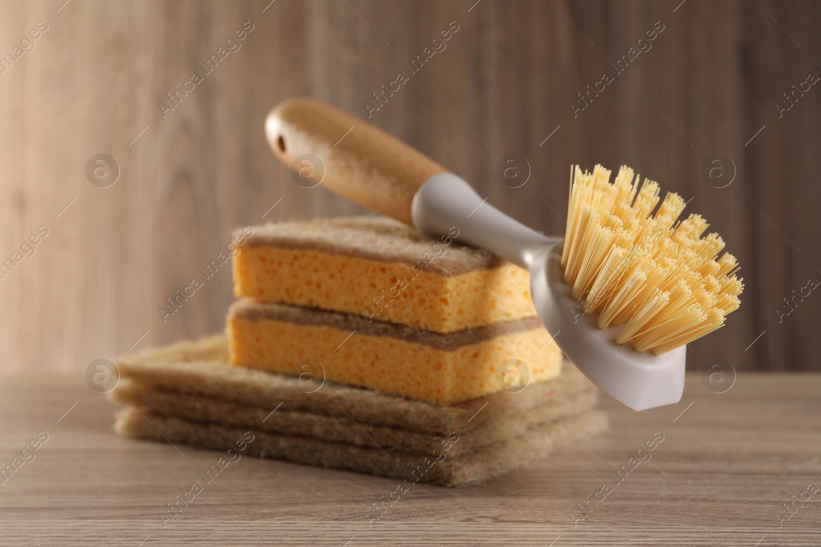 Photo of Cleaning brush and sponges on wooden table