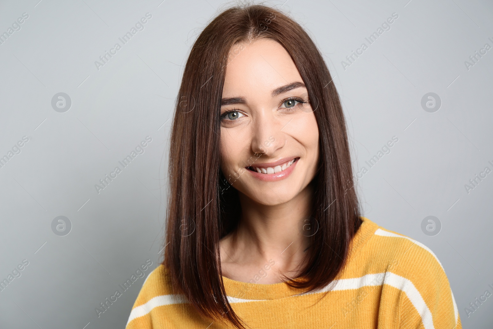 Photo of Portrait of pretty young woman with gorgeous chestnut hair and charming smile on light grey background