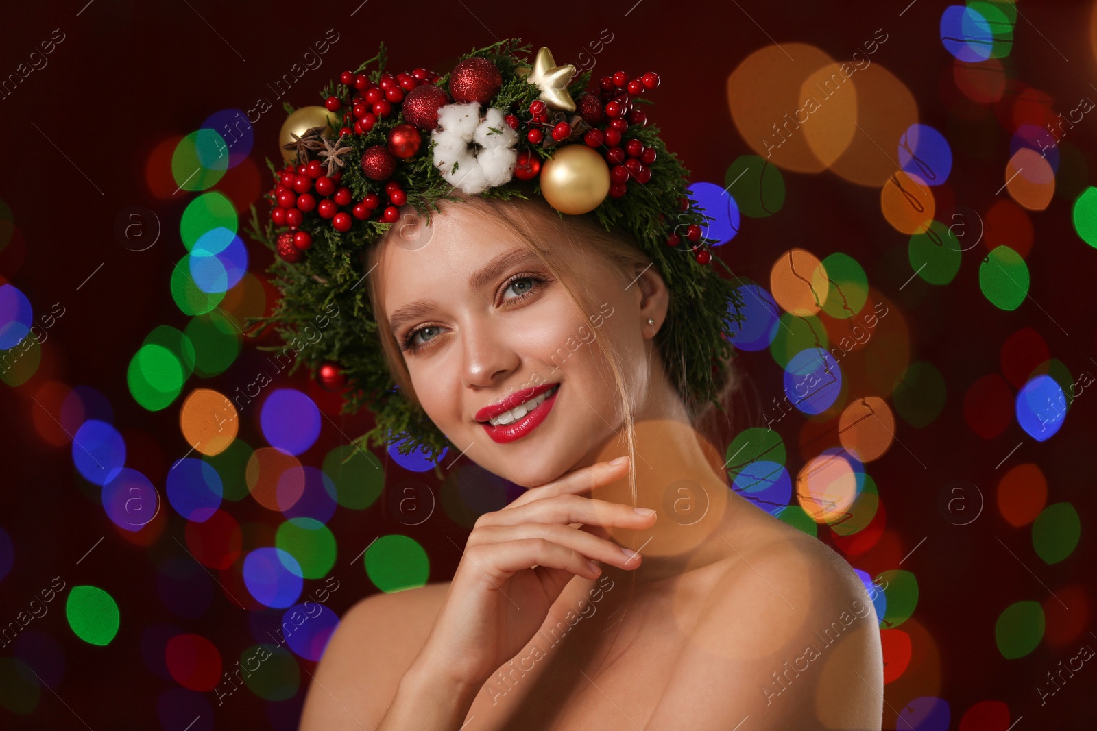 Photo of Beautiful young woman wearing Christmas wreath on blurred background. Bokeh effect