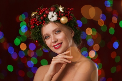 Photo of Beautiful young woman wearing Christmas wreath on blurred background. Bokeh effect