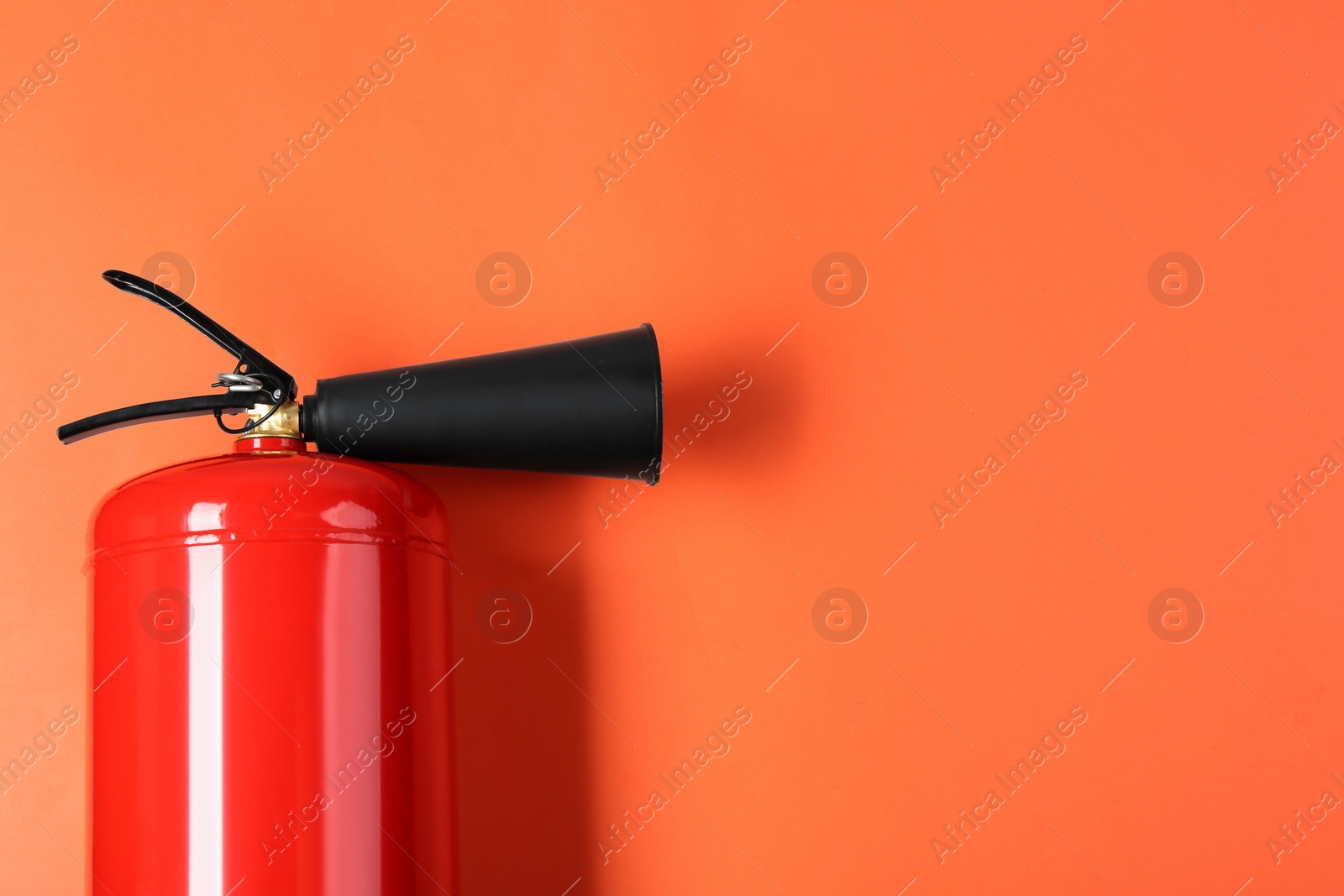 Photo of Fire extinguisher on orange background, top view. Space for text