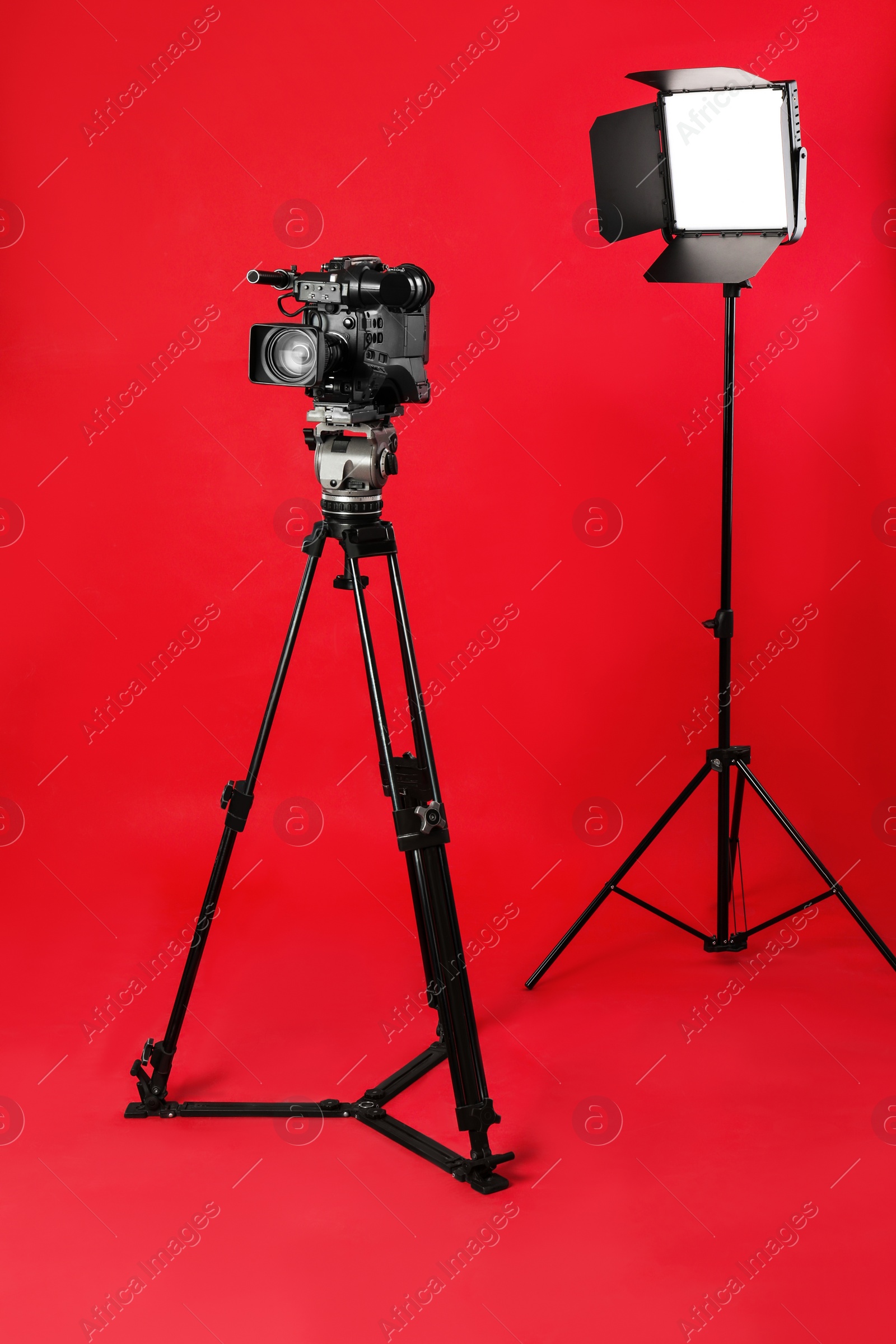 Photo of Professional video camera and lighting equipment on red background