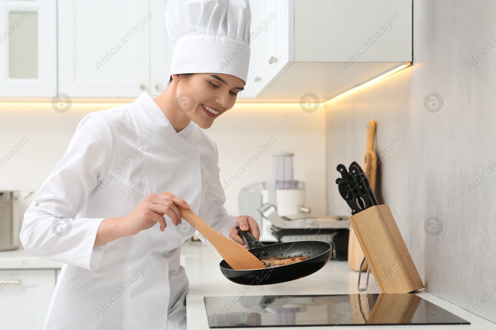 Photo of Happy chef cooking delicious meat with thyme in frying pan indoors