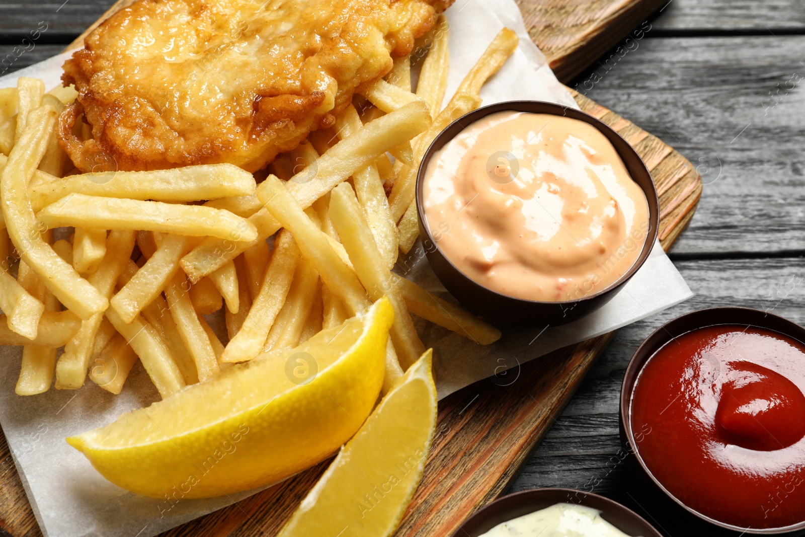 Photo of British traditional fish and potato chips on wooden table, closeup