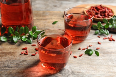 Photo of Healthy goji juice in glasses on wooden table