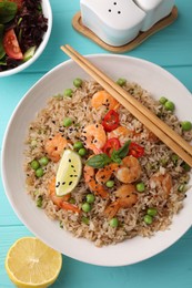 Tasty rice with shrimps and vegetables served on turquoise wooden table, flat lay