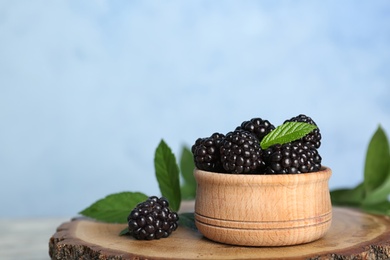 Photo of Bowl of fresh blackberry on table against color wall. Space for text