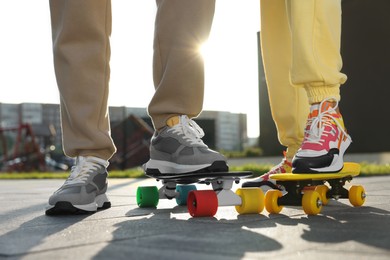 Photo of Woman and man with skateboards wearing stylish sneakers outdoors, closeup