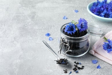 Photo of Dry tea leaves and cornflowers on light table. Space for text