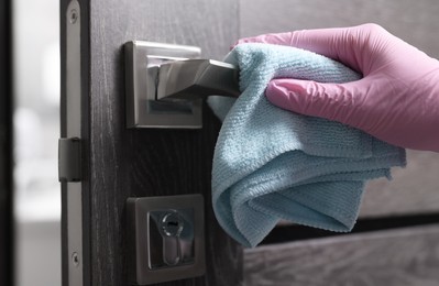 Woman wiping door handle with rag, closeup