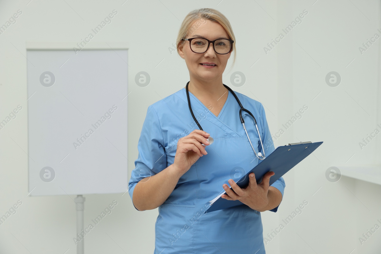 Photo of Professional doctor wearing uniform near flipchart in clinic