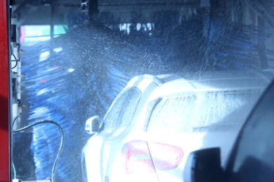Modern auto undergoing cleaning at car wash
