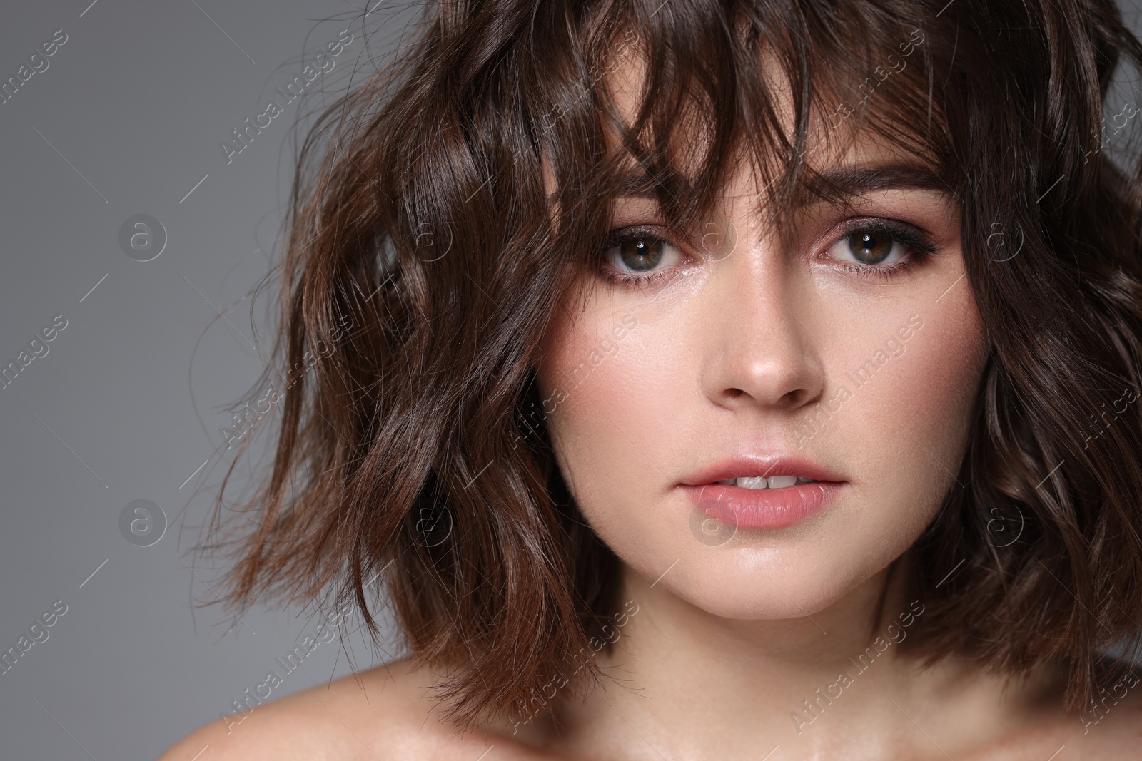 Photo of Beautiful young woman with wavy hairstyle on grey background