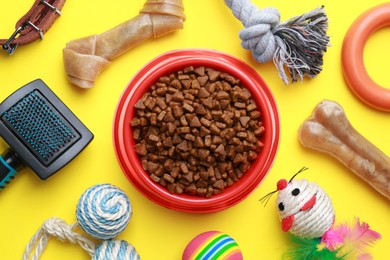 Photo of Flat lay composition with pet toys and feeding bowl on yellow background