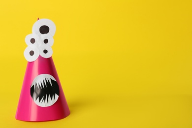 Photo of Funny pink monster on yellow background, space for text. Halloween decoration