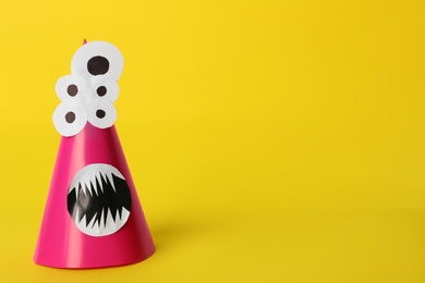 Funny pink monster on yellow background, space for text. Halloween decoration