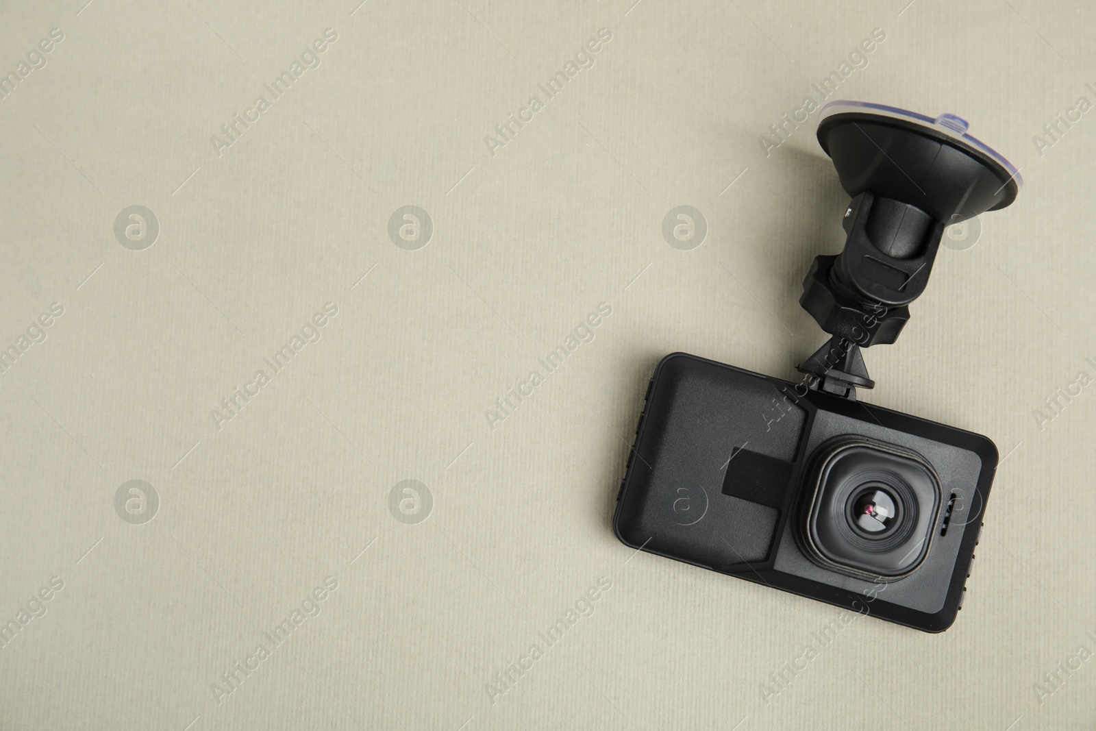 Photo of Modern car dashboard camera with suction mount on light background, top view. Space for text