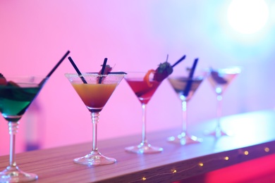 Photo of Different martini cocktails on table in bar, space for text