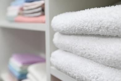 Photo of Stack of terry towels on shelf in linen shop, closeup. Space for text