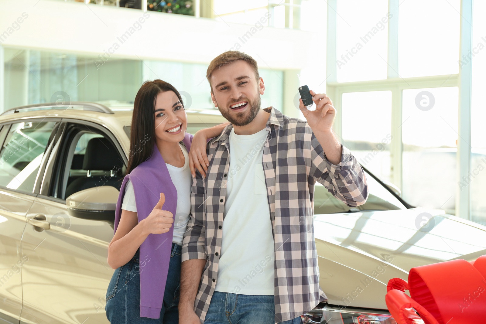 Photo of Happy couple with car key in modern auto dealership