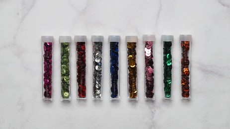 Photo of Many colorful sequins in containers on light grey background, top view