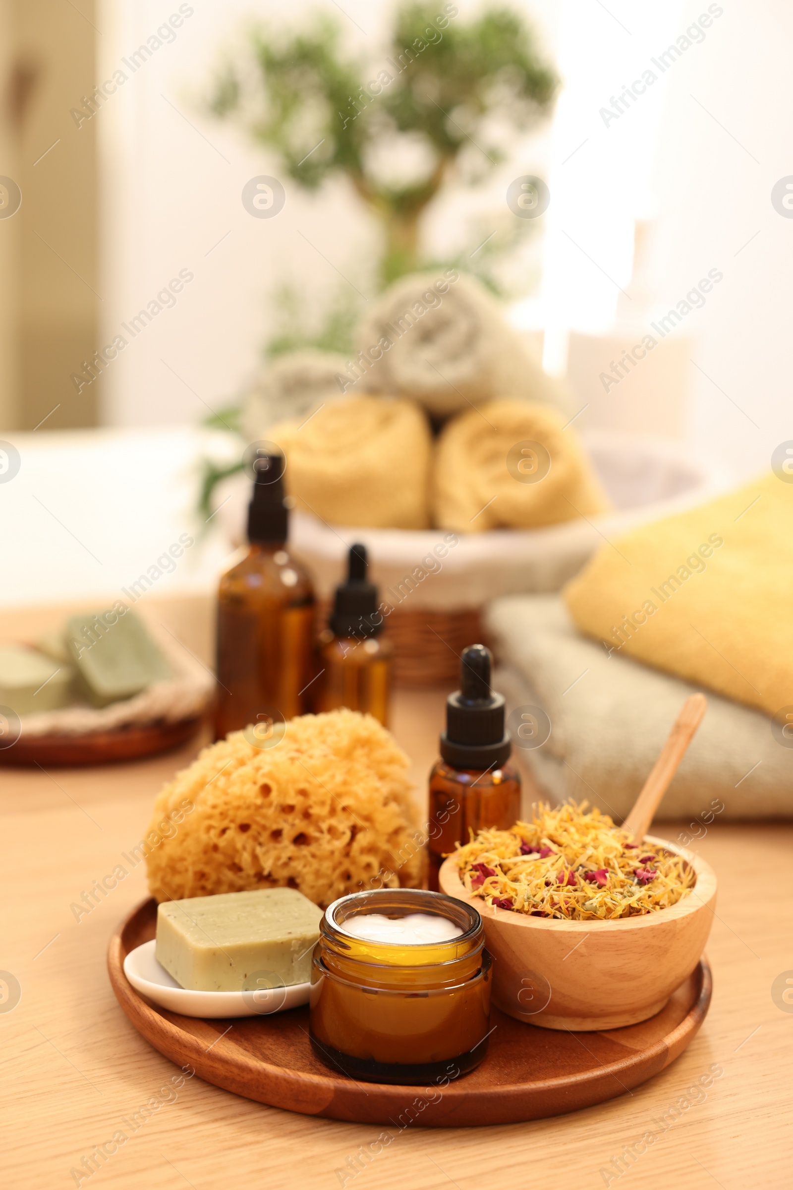 Photo of Dry flowers, loofah, soap bar, bottle of essential oil and jar with cream on wooden table indoors, space for text. Spa time