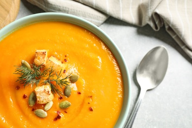 Delicious pumpkin soup in bowl on grey table, top view