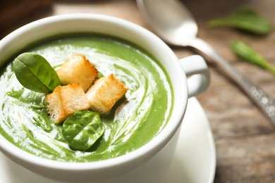 Photo of Fresh vegetable detox soup made of spinach with croutons in dish on table, closeup